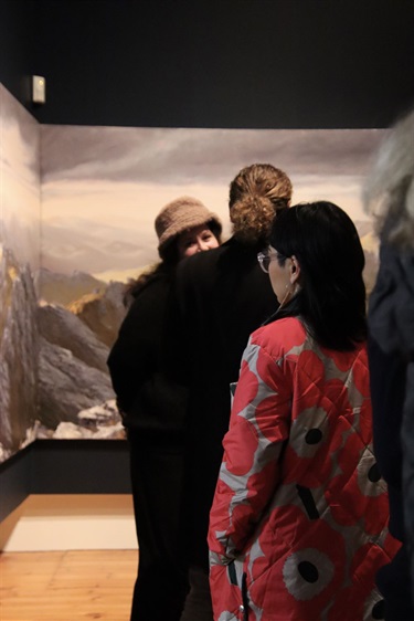 Woman standing and viewing a large-scale-landscape oil painting by Tasmanian artist Harrison Bowe