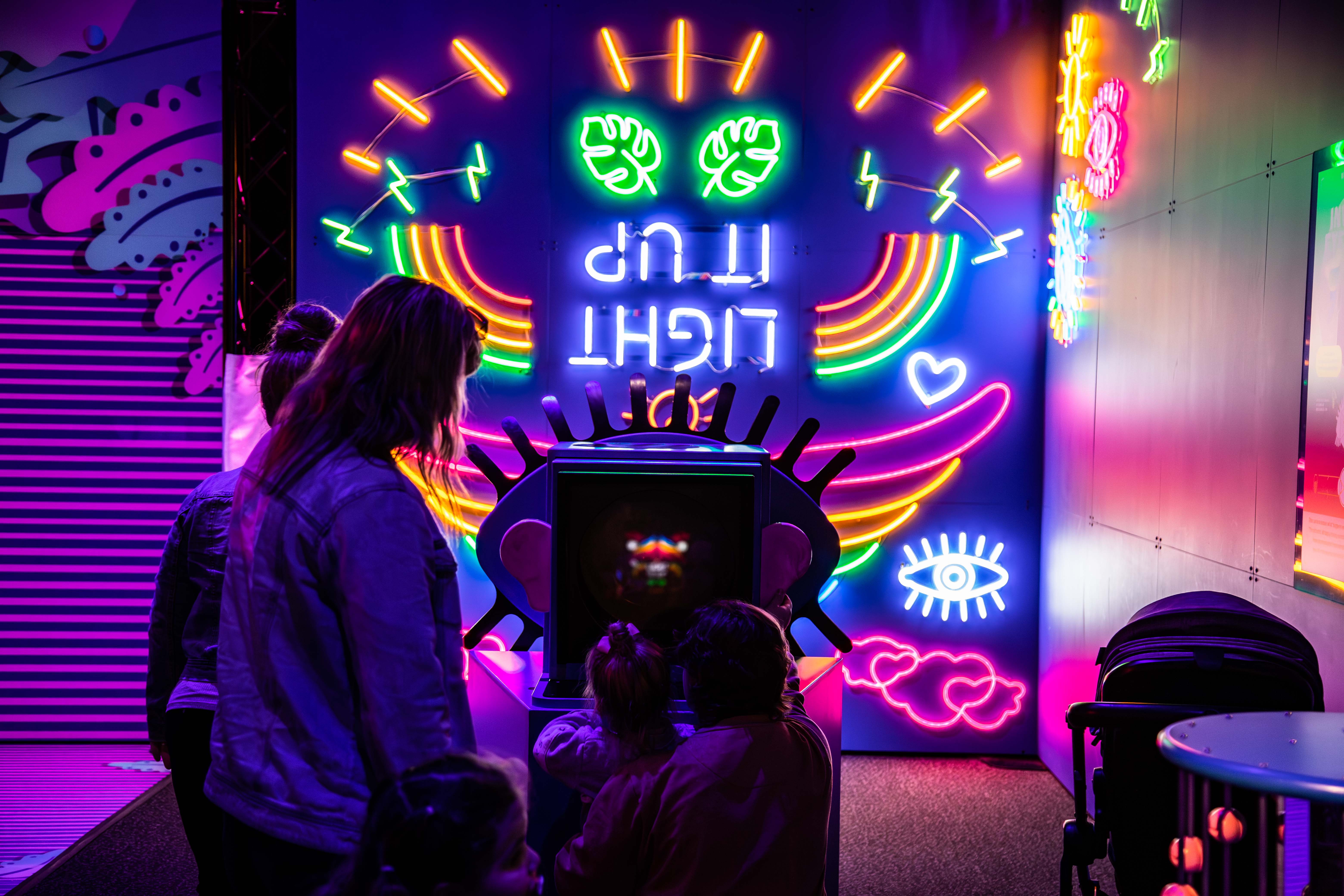 Families standing in front of a multi-coloured glowing game module