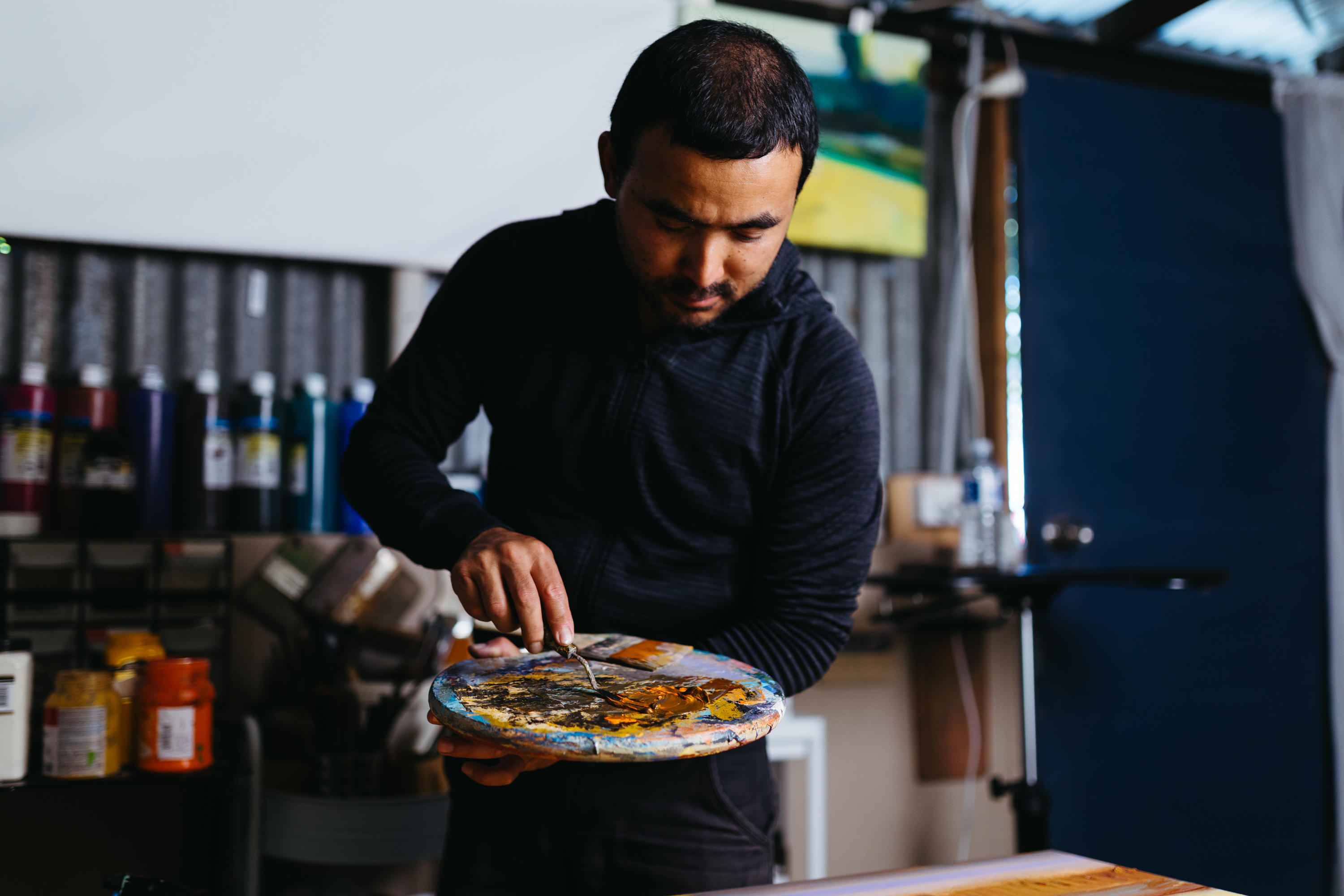 RISE artist Jeewan Suwal mixes paint on a palette