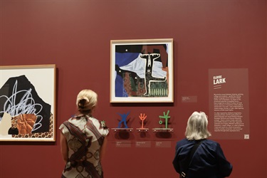 Two visitors look at artworks by Eloise Lark
