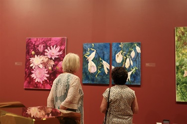 Two visitors look at the artworks of Maggie May Jeffries