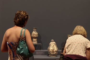 Two visitors look at the artworks of Rosanagh May