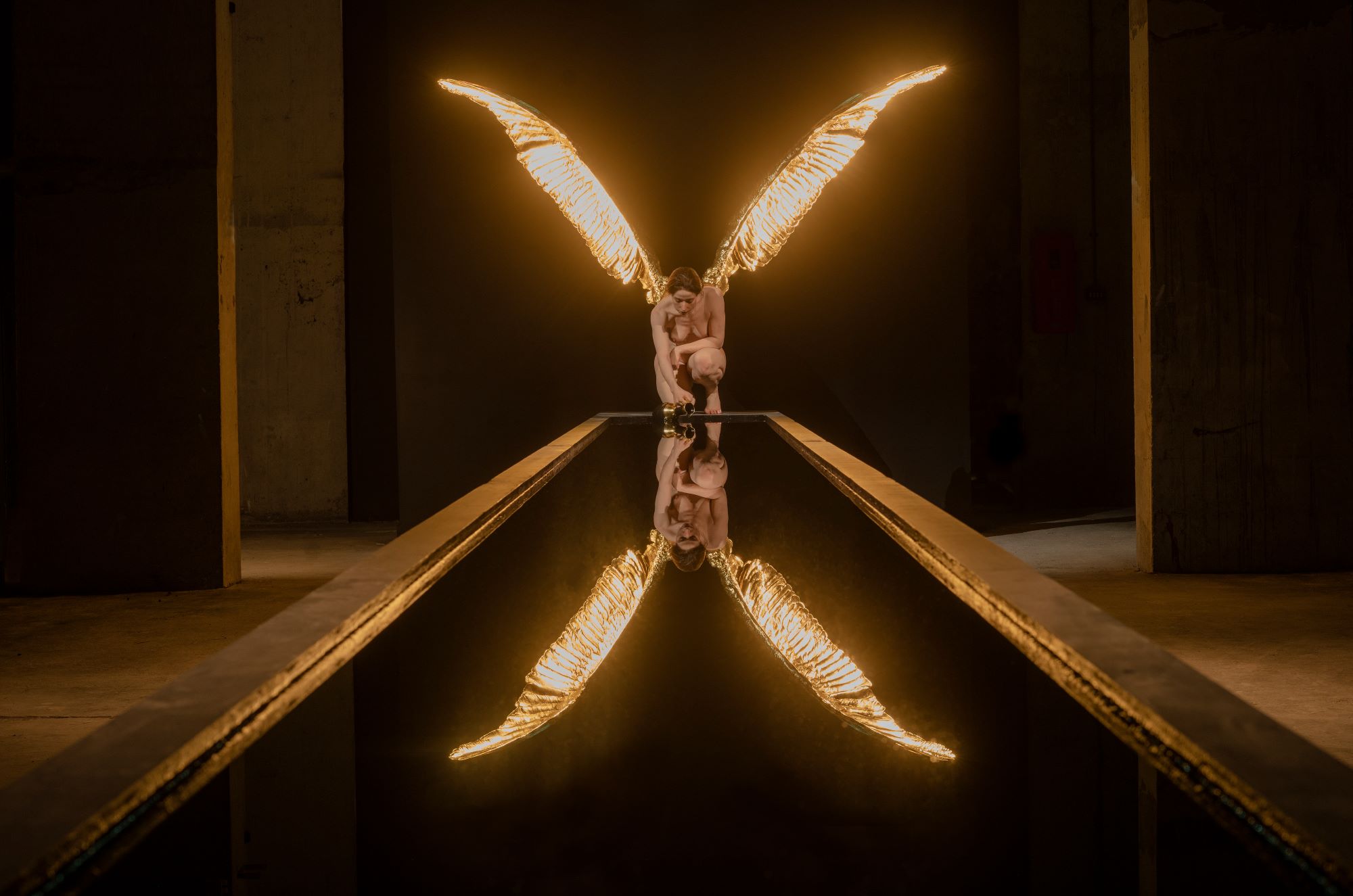 The Messenger by Sam Jinks, a hyper-real sculpture of the Greek goddess Iris with golden wings, kneeling in front of a mirror.