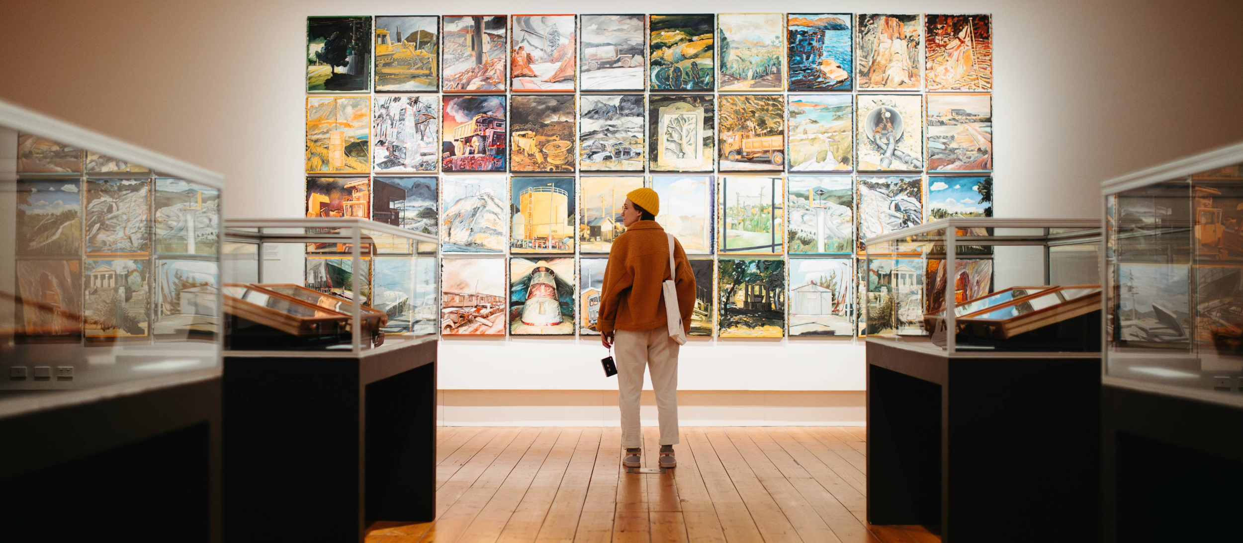 A visitor stands in front of a collection of paintings